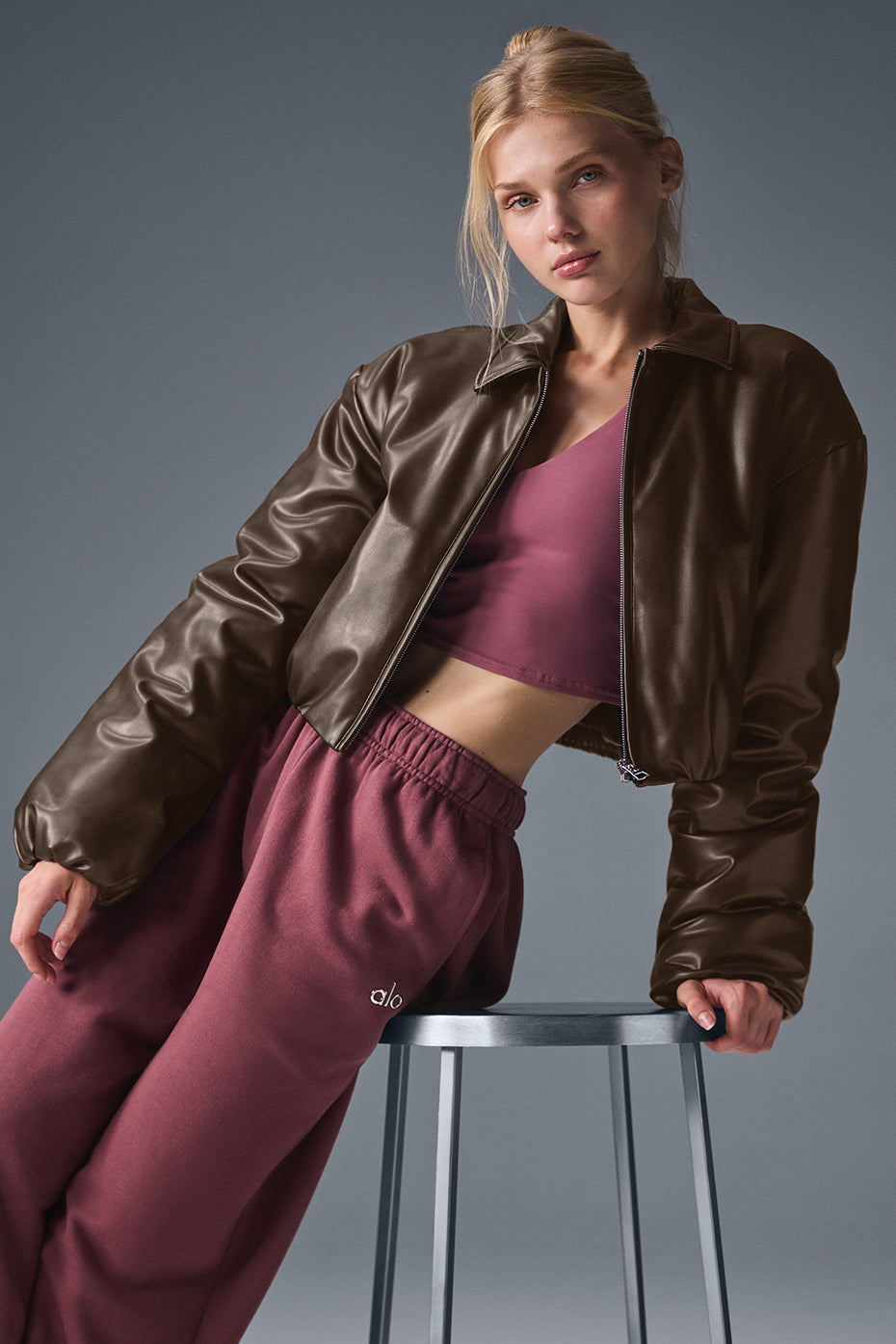 Back view of uibok brown women's cropped leather bomber jacket with ribbed hem