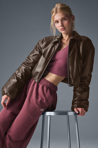 Back view of uibok brown women's cropped leather bomber jacket with ribbed hem