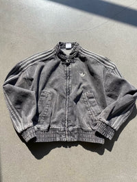 Black denim jacket with Adidas logo on a gray surface