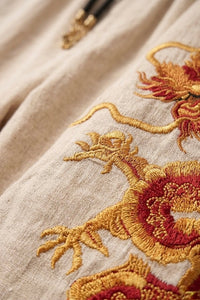 Extreme close-up shot of intricate red and metallic gold traditional Chinese dragon embroidery on a textured casual fabric leg.