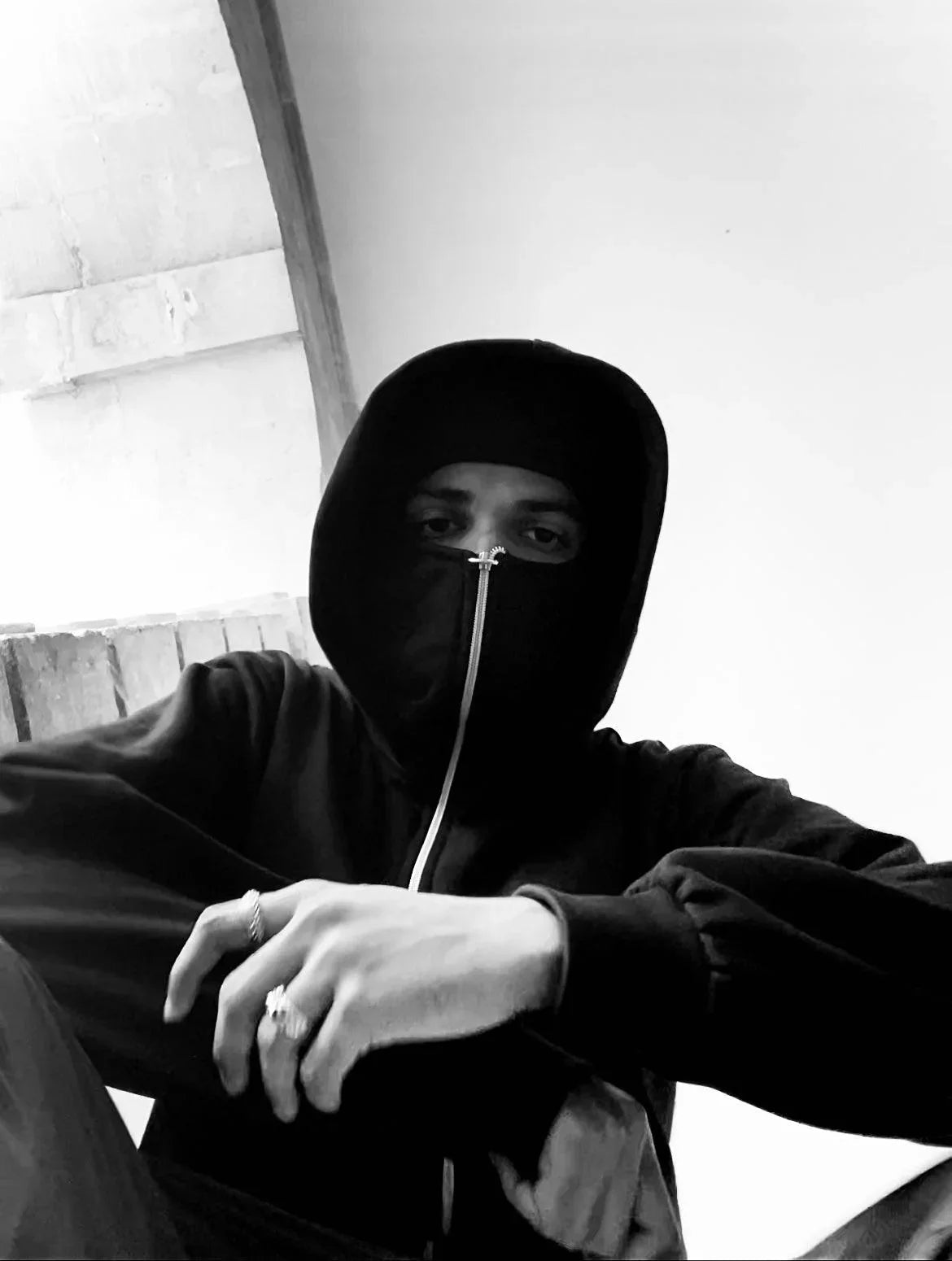 Streetwear model in black zip-up hoodie with hood up, posing indoors, urban Y2K style