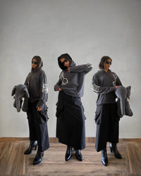 Woman in Y2K streetwear: graphic hoodie, cargo skirt, boots, sunglasses, holding elephant plush
