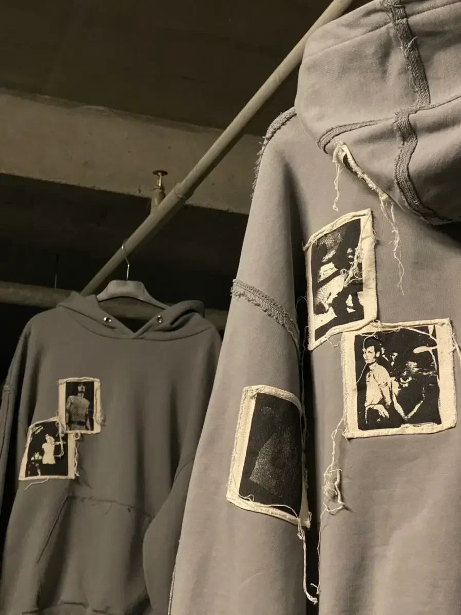 Gray streetwear hoodies with raw hem and vintage photo patches, hanging on a rack