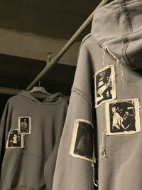 Gray streetwear hoodies with raw hem and vintage photo patches, hanging on a rack