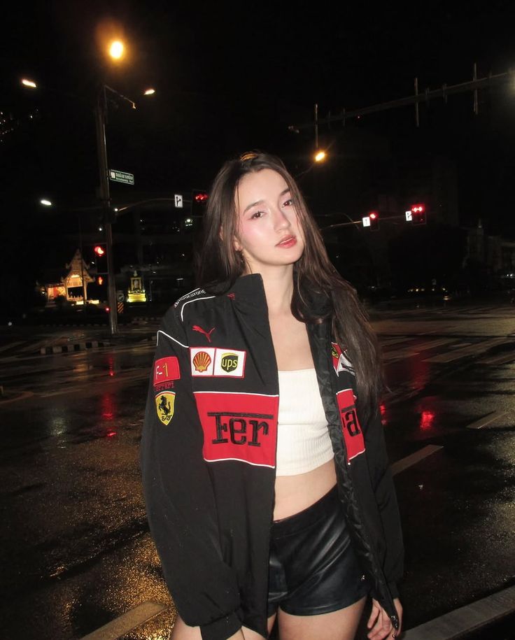 Woman black ferrar jacket with logos on a street at night