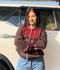Woman wearing brown Spider-Man hoodie with red graphic and blue jeans outdoors