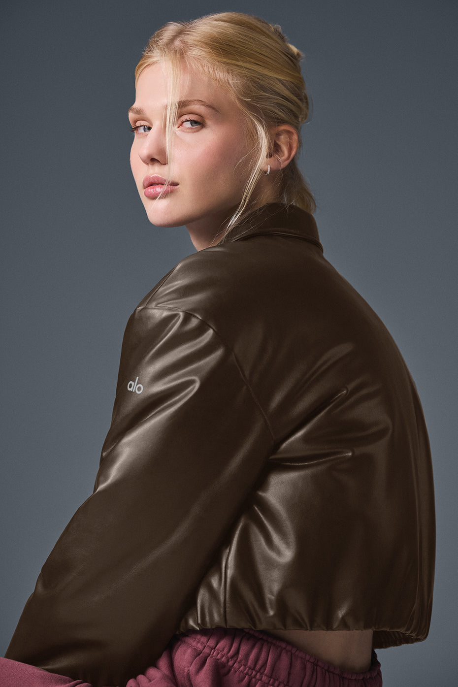 Back view of uibok brown women's cropped leather bomber jacket with ribbed hem